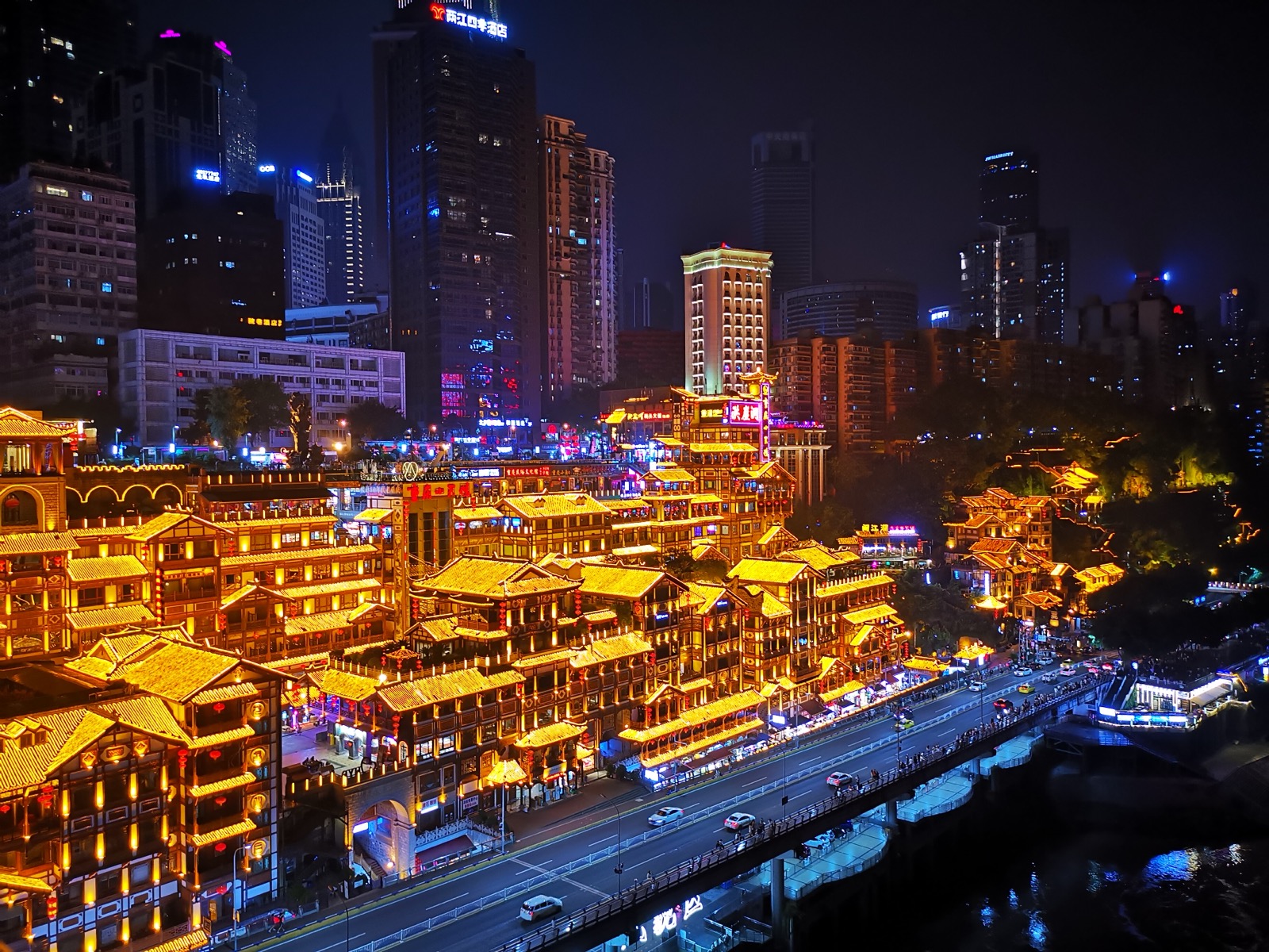 Hongyadong’s multilevel riverside buildings glowing with golden lights at night in Chongqing
